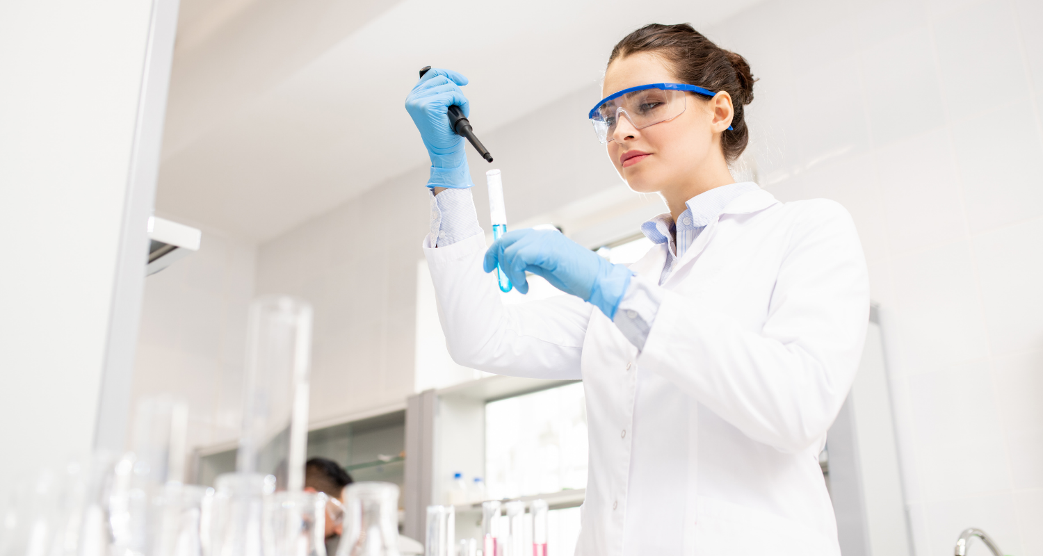 Científica realizando pruebas de Demanda Química de Oxígeno (DQO) en laboratorio, utilizando pipeta y tubos de ensayo, cumpliendo con la normativa de medición